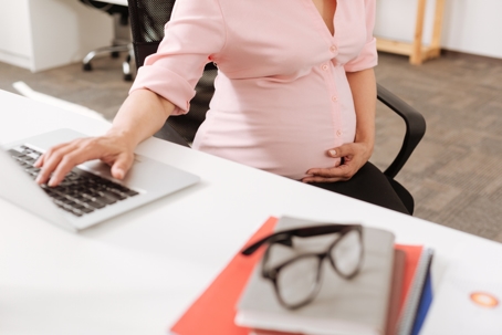 Pregnant woman holding her belly at work